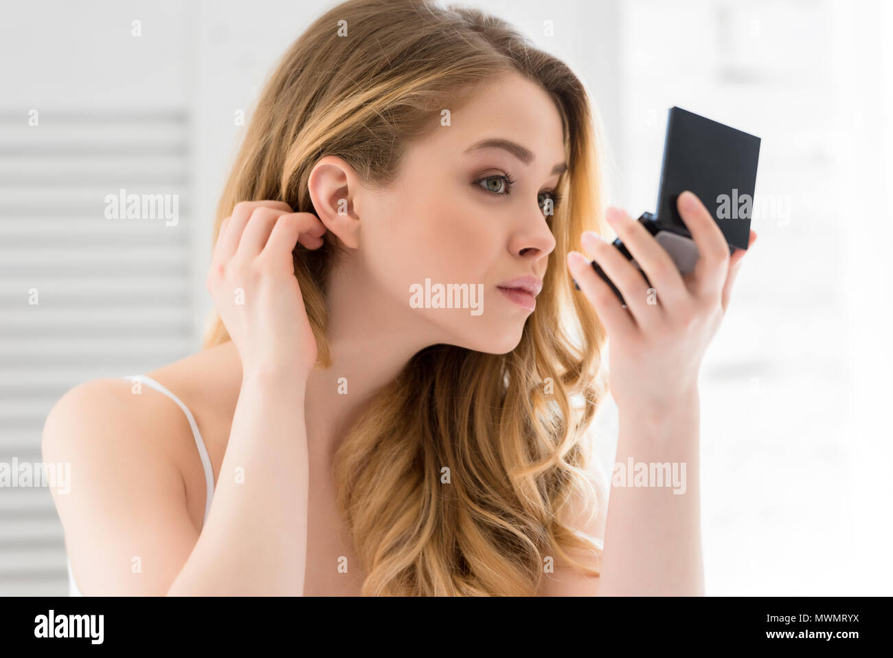 Attraktive junge Frau in einem kleinen Spiegel auf der Suche Stockfoto