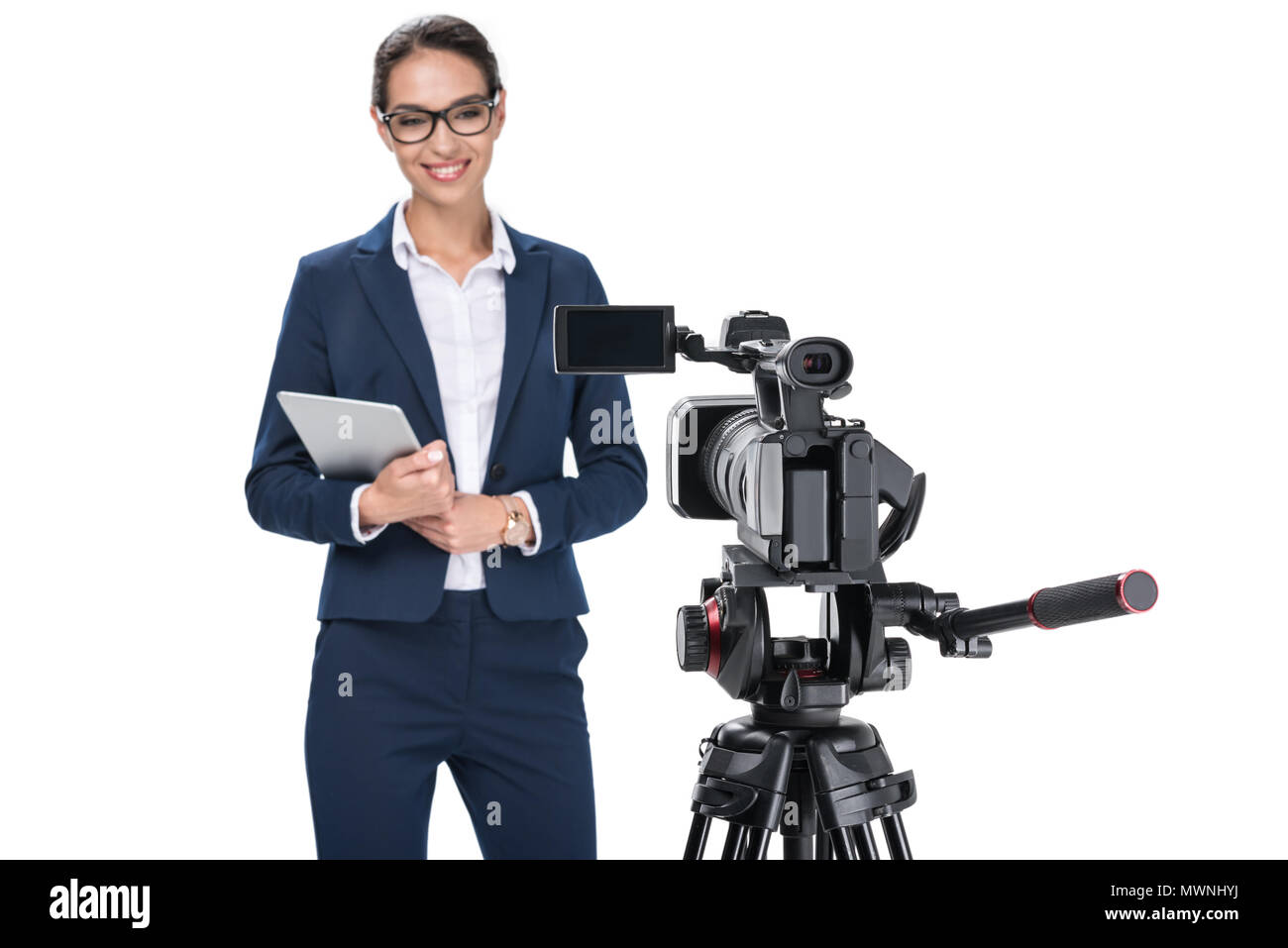 Lächelnd weibliche Nachrichtensprecher mit digitalen Tablet Stand vor der Kamera, auf weissem isoliert Stockfoto