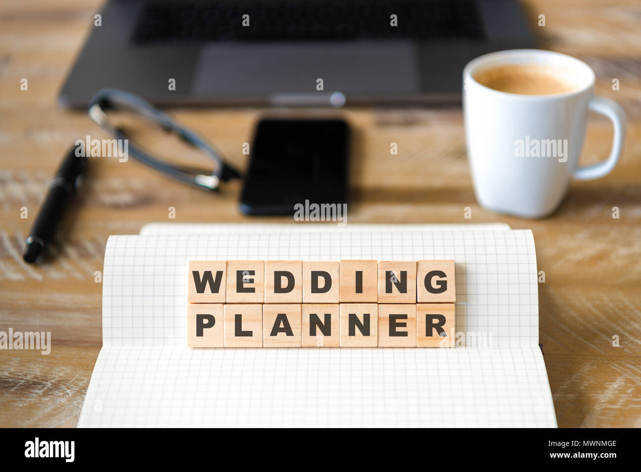 Nahaufnahme auf das Notebook um Holz Tisch Hintergrund, auf Holzblöcken mit Buchstaben, Wedding Planner Text konzentrieren. Stockfoto
