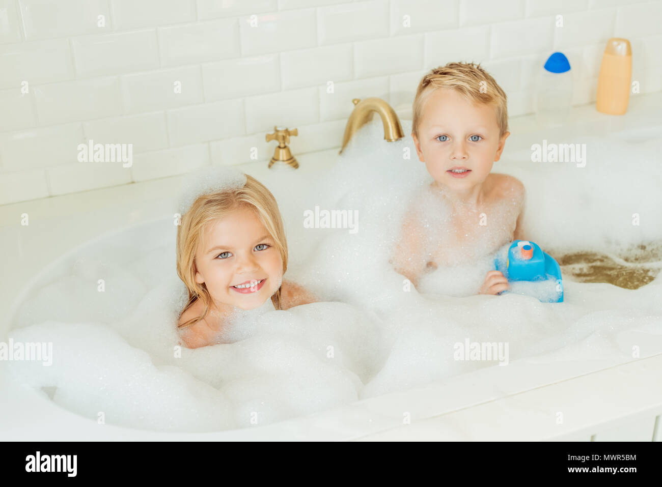 Entzückenden kleinen Bruder und Schwester lächelnd in die Kamera beim zusammen spielen in der Badewanne mit Schaum Stockfoto