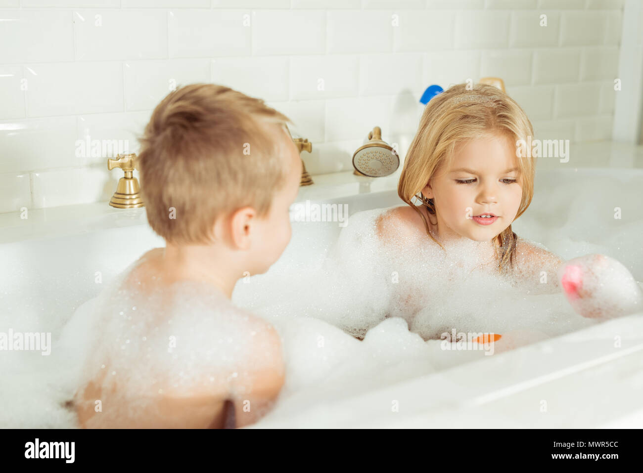 Entzückenden kleinen Bruder und Schwester spielen zusammen in der Badewanne mit Schaum Stockfoto