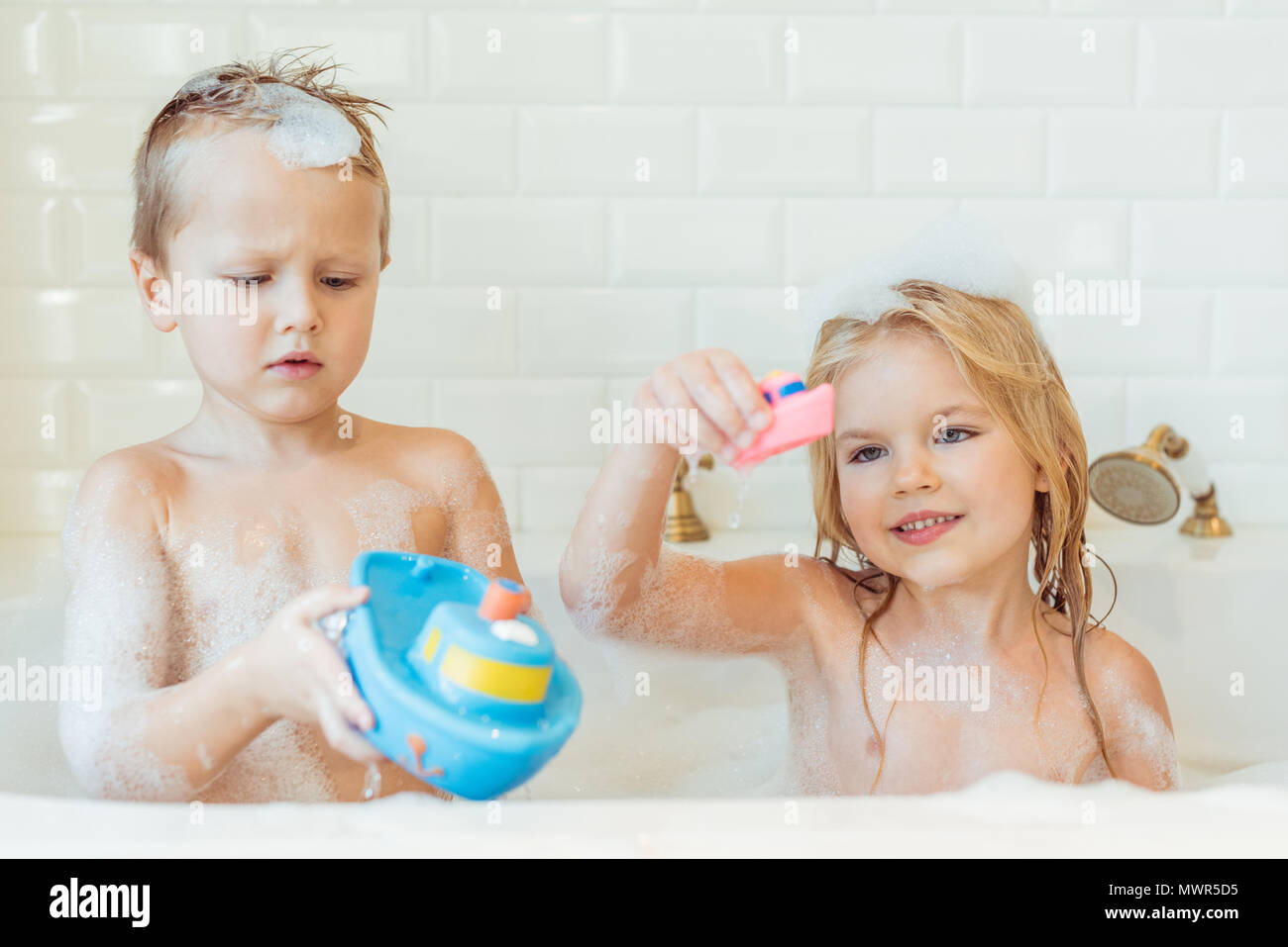 Cute gerne kleine Kinder mit Spielzeug spielen in der Badewanne Stockfoto