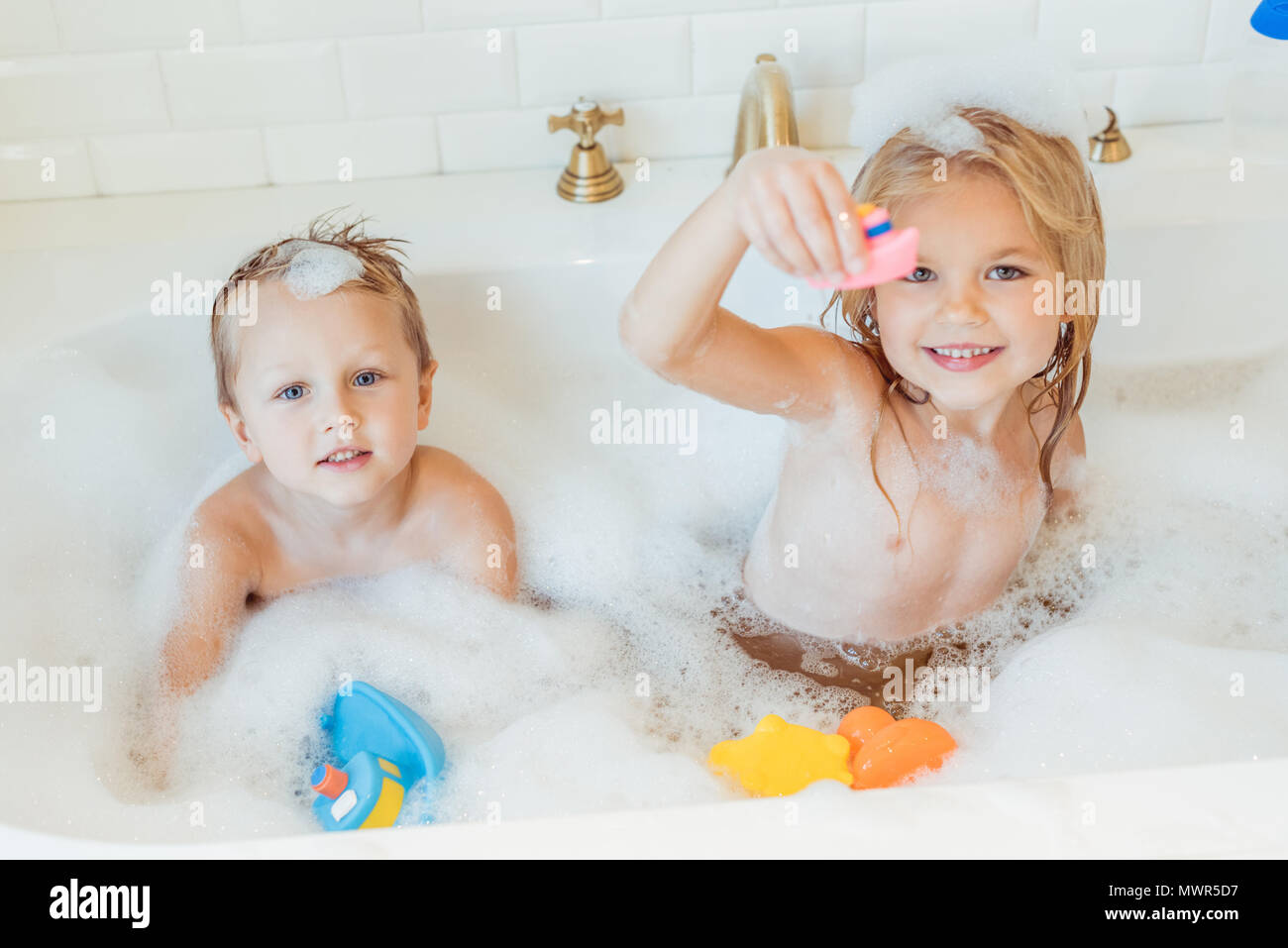 Süße kleine Bruder und Schwester spielen mit Spielzeug und ein Lächeln auf die Kamera in der Wanne Stockfoto