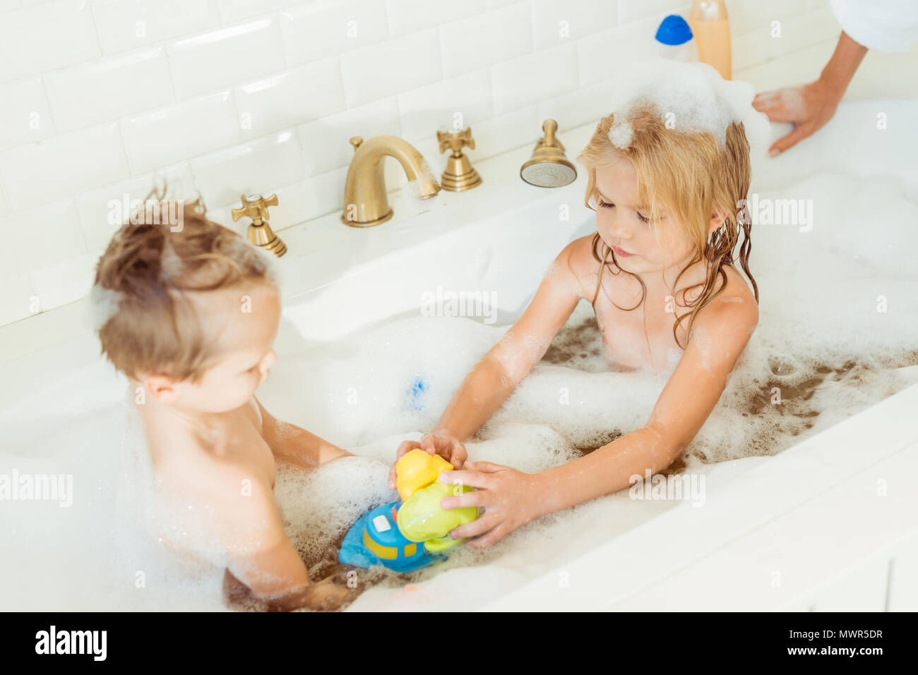 Süße kleine Bruder und Schwester mit Spielzeug spielen in der Badewanne Stockfoto