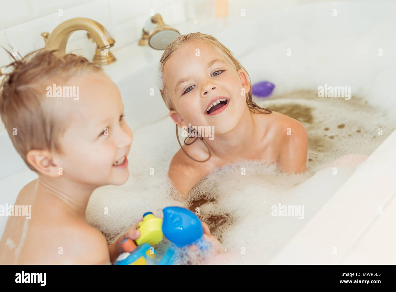 Glückliche kleine Bruder und Schwester spielen zusammen in der Badewanne Stockfoto