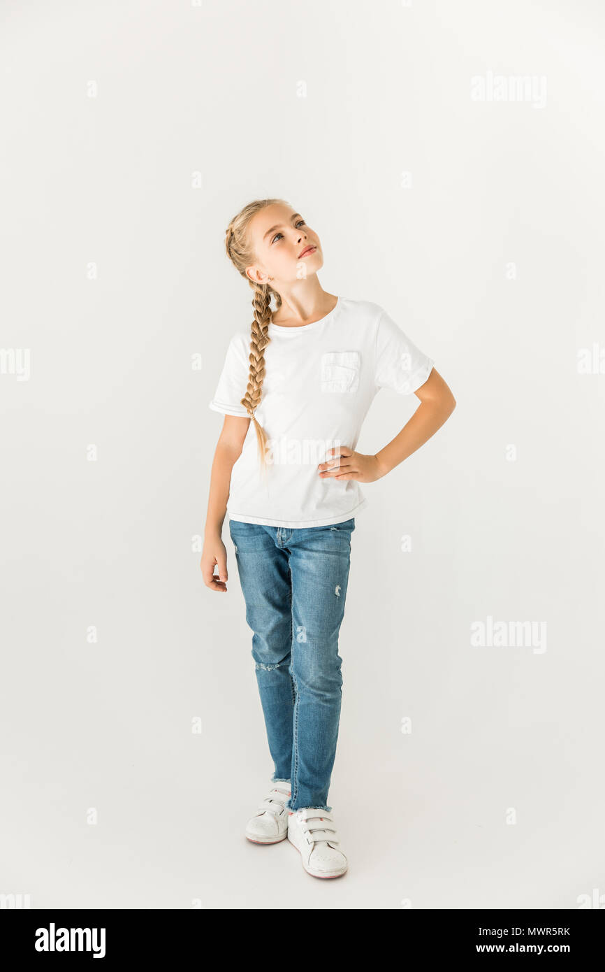 Schöne nachdenkliche Kind stehend mit der Hand auf der Hüfte und auf Weiß isoliert Stockfoto