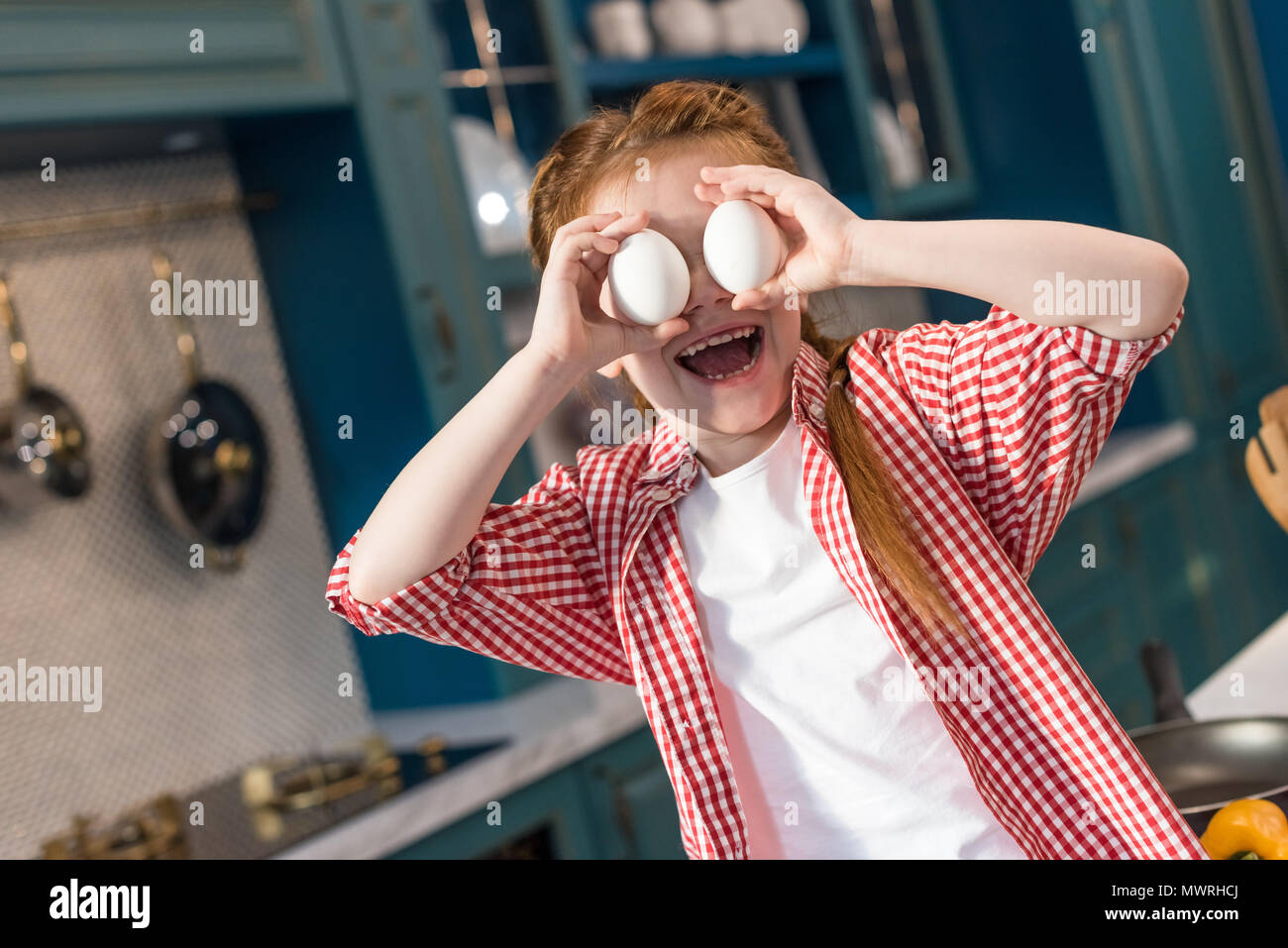 Adorable kleine Kind holding Eier und lächelnd an Küche Stockfoto