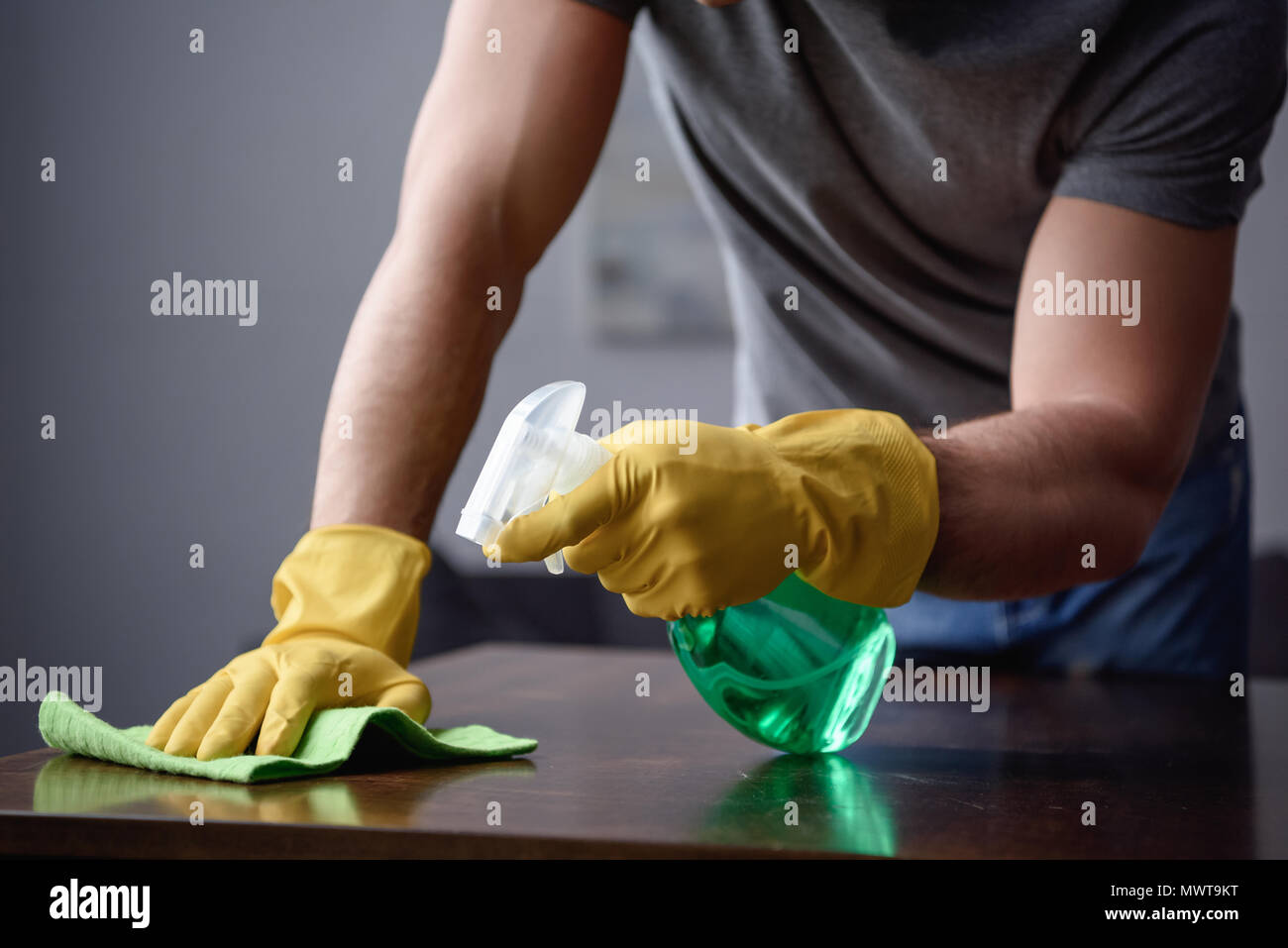 Zugeschnittenes Bild des Menschen Reinigung Tisch im Wohnzimmer mit Sprühflasche und rag Stockfoto