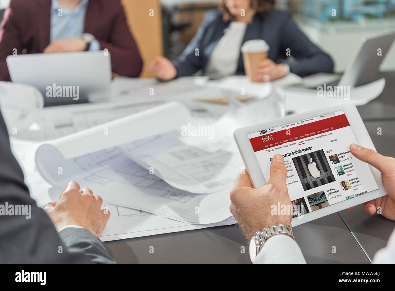 7/8 Schuß des Architekten mit Tablette mit der BBC-Website auf dem Bildschirm während Konferenz Stockfoto