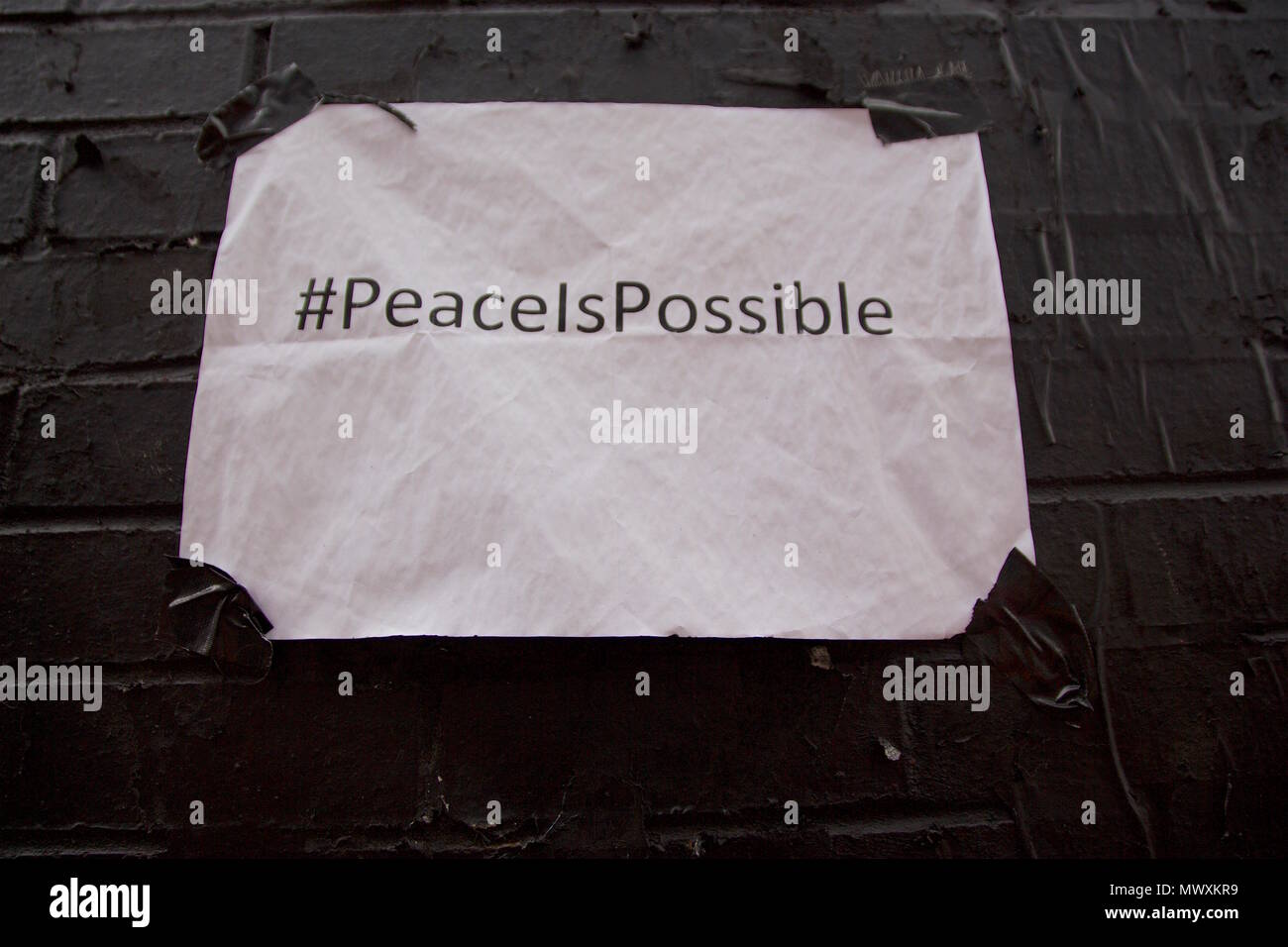 White Paper mit Klebeband an der Wand auf die ebor Street, Shoreditch, London sagen # PeaceIsPossible, die neben einem Frieden Wandbild von Ben EINE Stockfoto