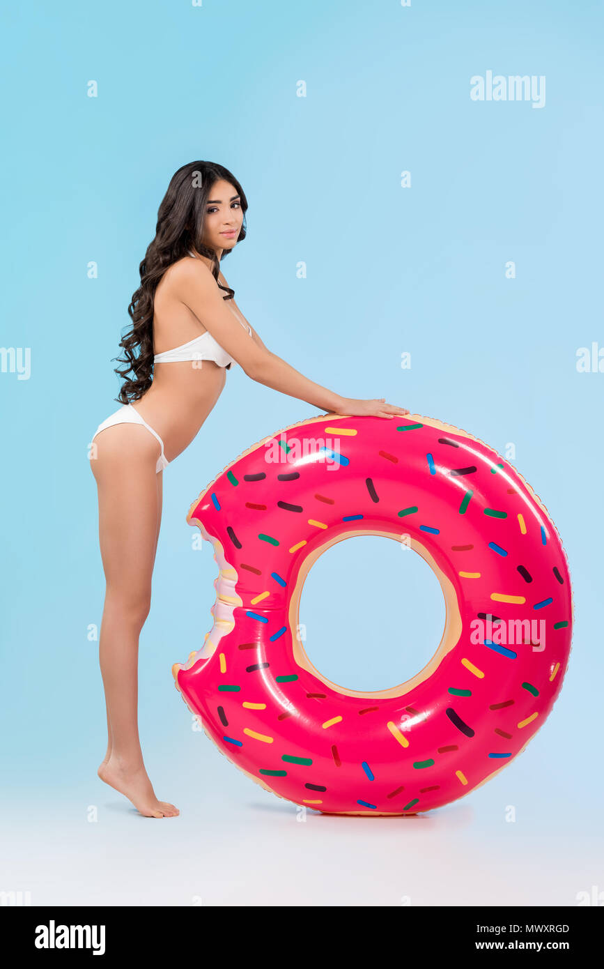 Attraktives Mädchen mit aufblasbaren Donut ring posiert, isoliert auf Blau Stockfoto