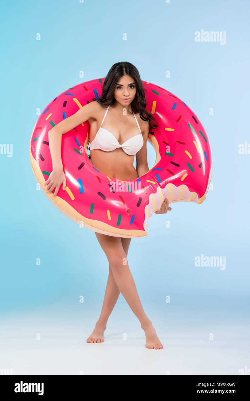 Schöne Mädchen mit aufblasbaren Donut ring posiert, isoliert auf Blau Stockfoto