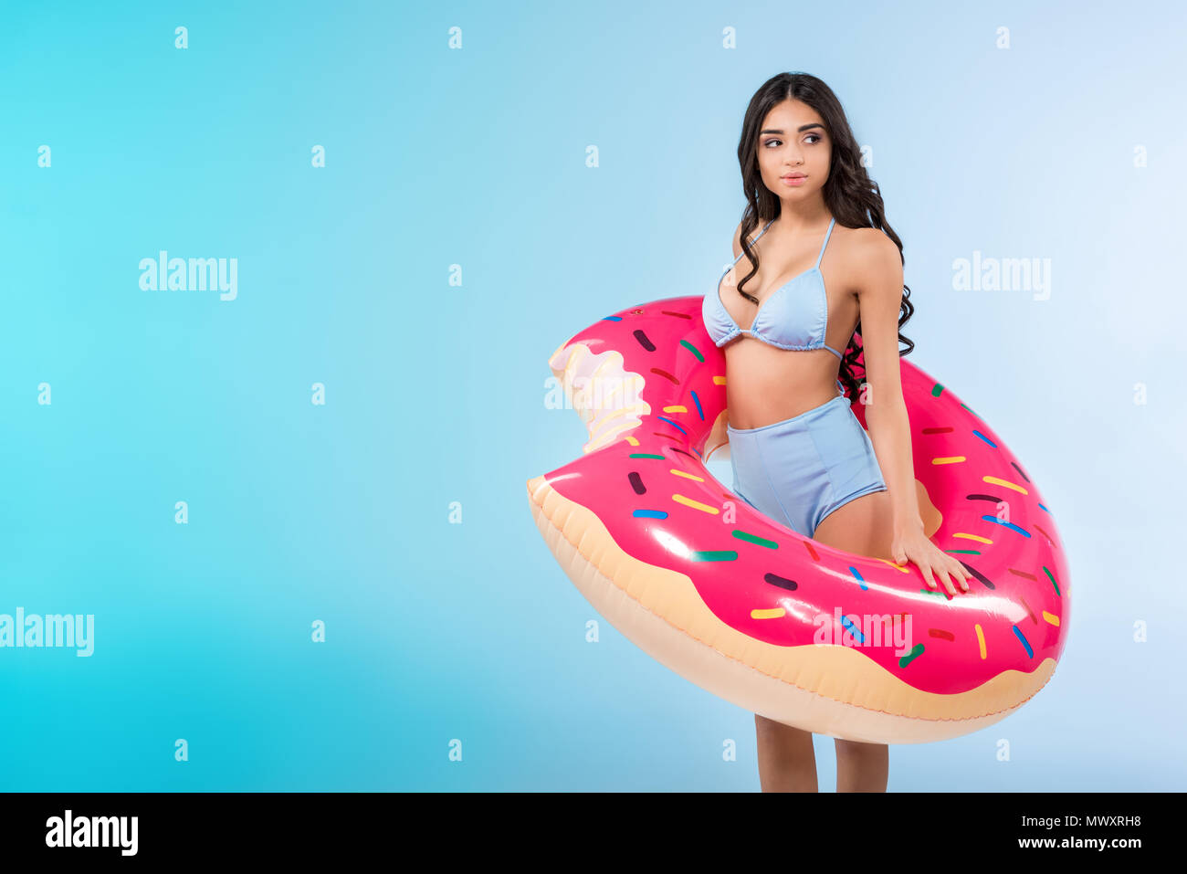 Hübsches Mädchen mit aufblasbaren Donut ring posiert, isoliert auf Blau Stockfoto