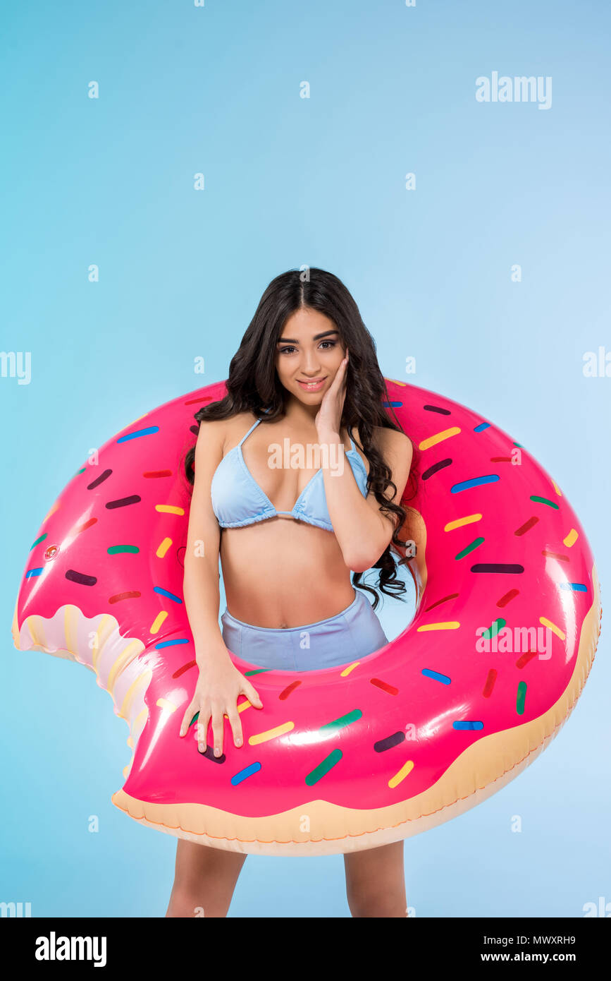 Schlankes hübsches Mädchen mit aufblasbaren Donut ring posiert, isoliert auf Blau Stockfoto