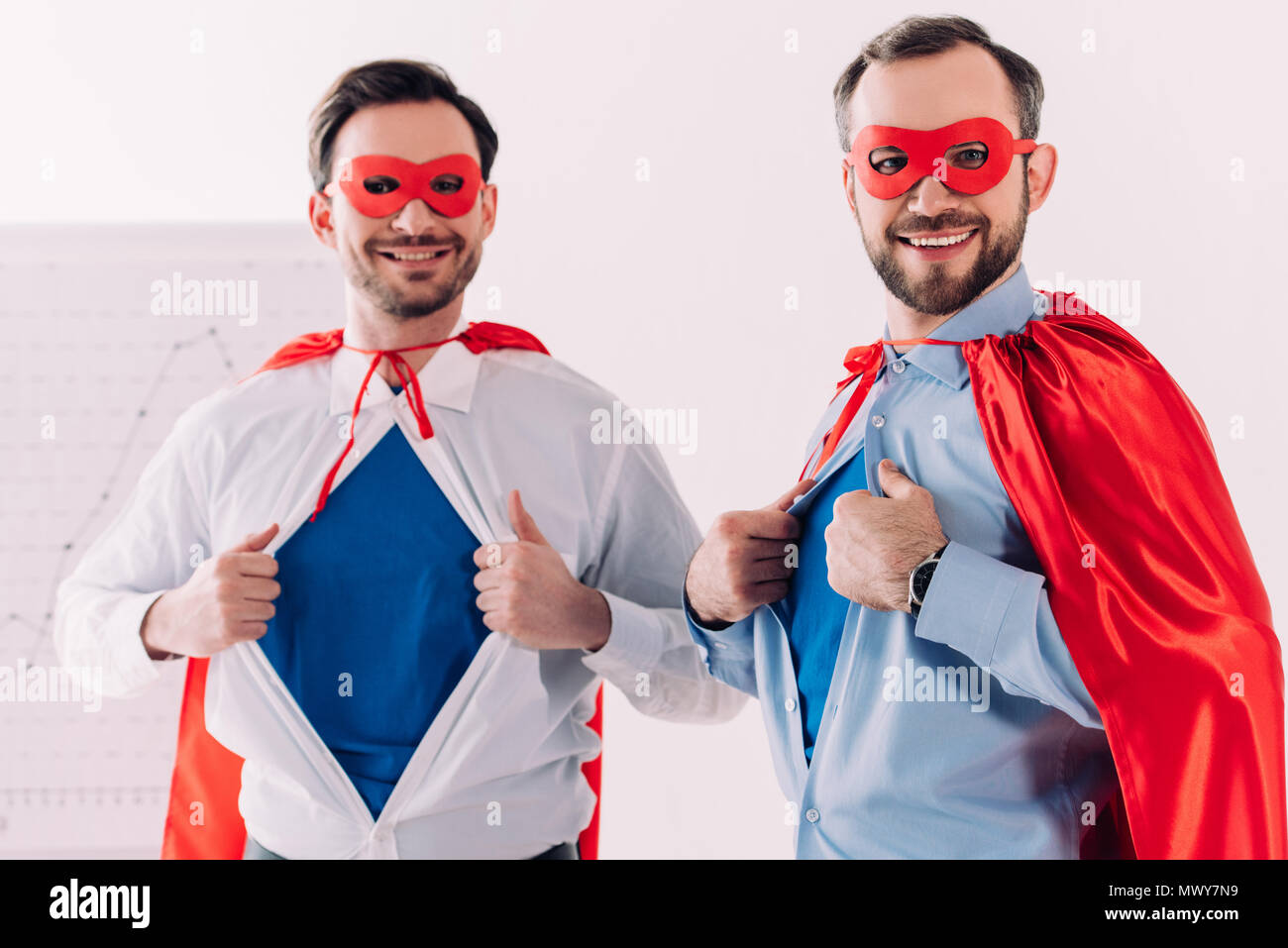 Schön super Geschäftsleute in Masken und Umhänge mit blauen Shirts im Büro Stockfoto