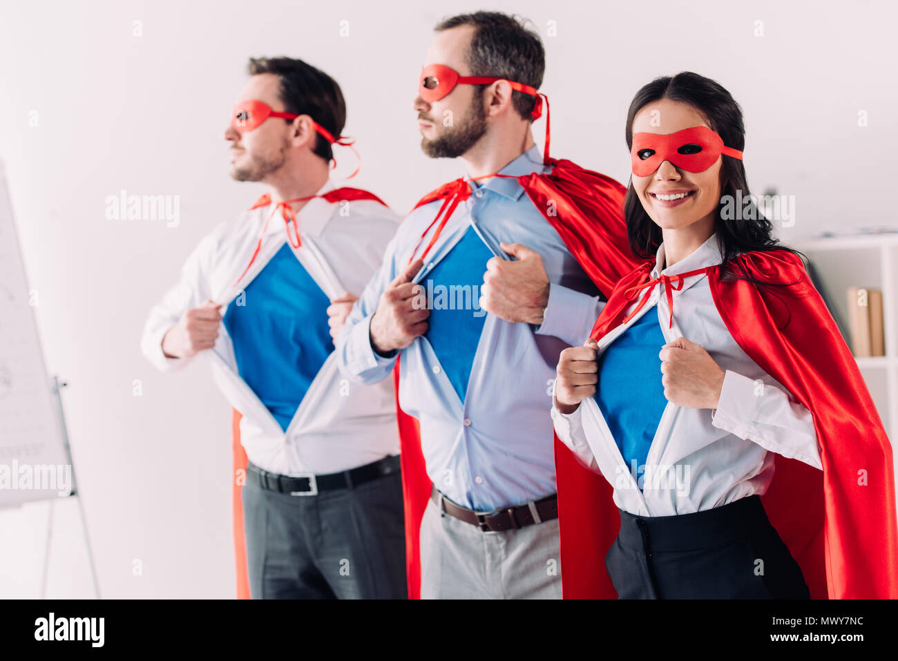 Super Geschäftsleute in Masken und Umhänge mit blauen Shirts im Büro Stockfoto