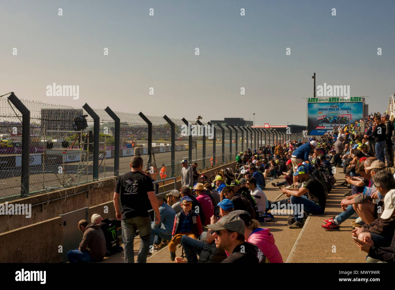 19./20. Mai 2018. Le Mans, Frankreich. Hinter die Kulissen der MotoGP. Zuschauer mit Blick auf Start Ziel Linie der Rennstrecke. Ein großer Bildschirm am Ende des Grand Stand ist bereit, die Nähe zu Relais Aktion der Tage Racing. Es ist eine helle, sonnige Tag mit einem blauen Himmel. Stockfoto