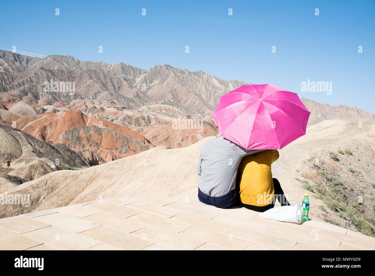 Paar genießt die Aussicht durch einen Regenschirm bei Zhangye-Danxia - Geopark, Provinz Gansu, China geschützt Stockfoto