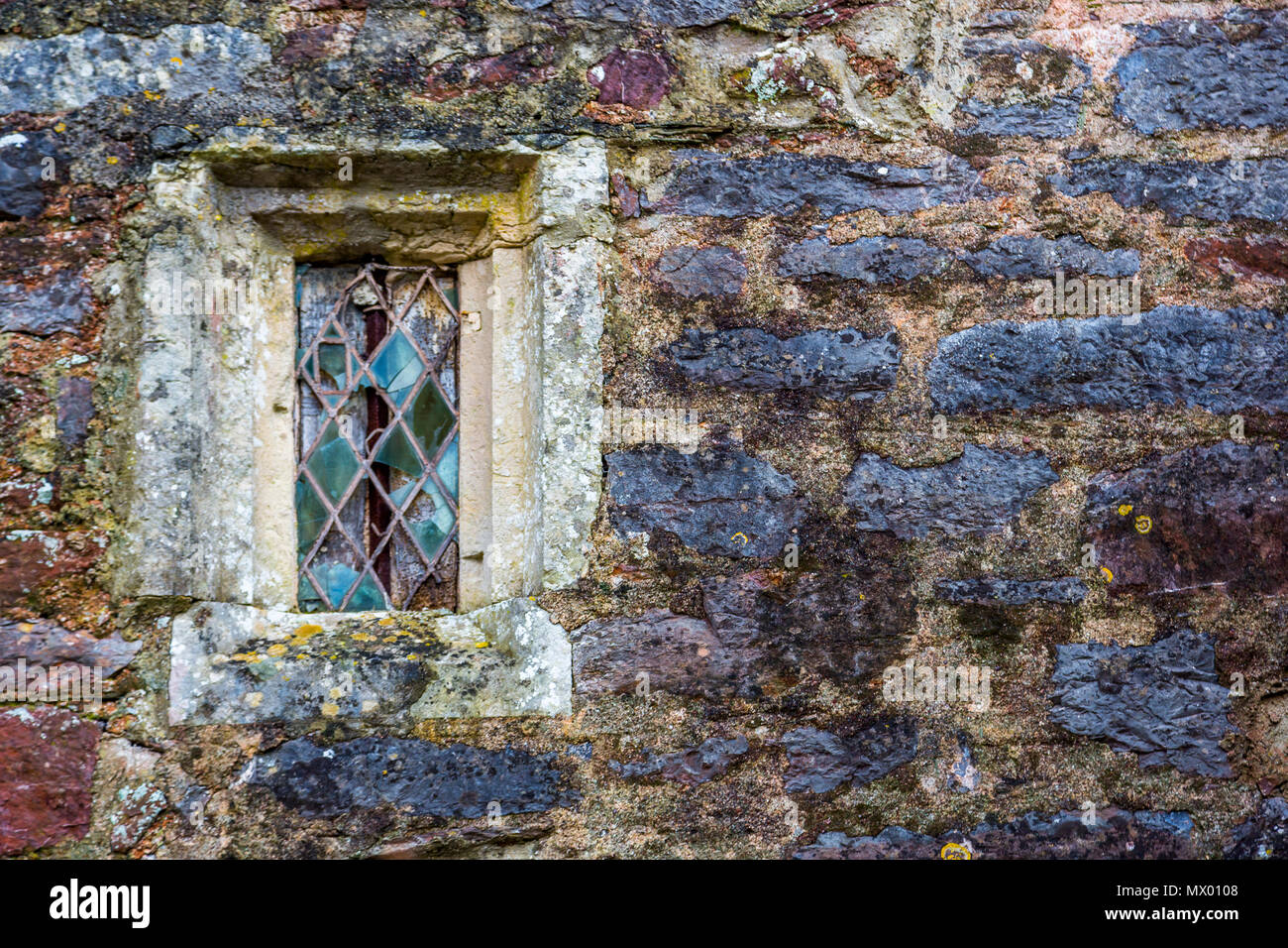 Fenster mit Fensterkreuz mit kunstverglasungen in einem alten steinernen Kirche. Stockfoto