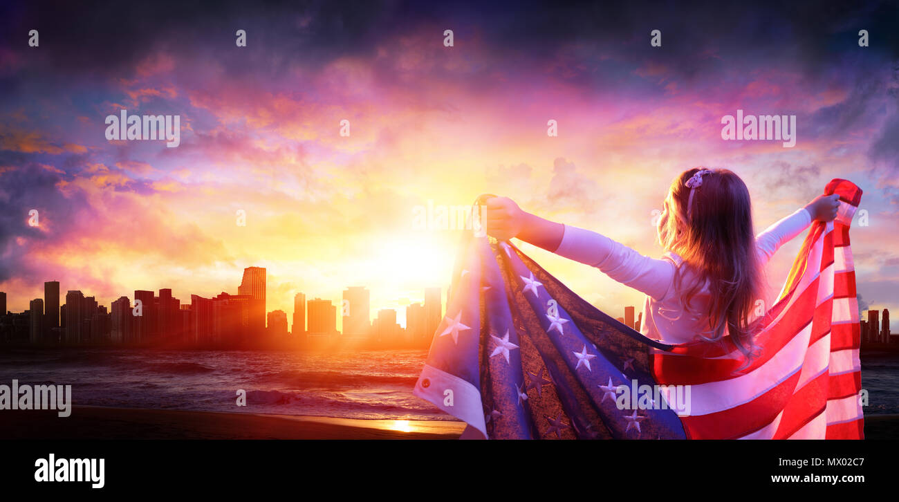 Kleines Mädchen in Freiheit mit amerikanischer Flagge - Stadt bei Sonnenuntergang Stockfoto