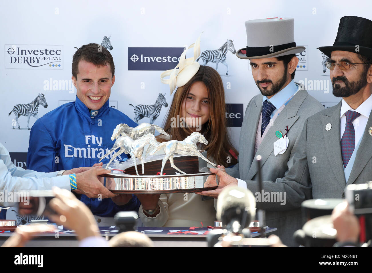 William Buick (links), Hamdan Bin Mohammed Al Maktoum (2. rechts) und Mohammed Bin Rashid Al Maktoum (rechts) nach masar gewinnt den Investec Derby beim Derby Tag der 2018 Investec Derby Festival in Epsom Downs Racecourse. Stockfoto