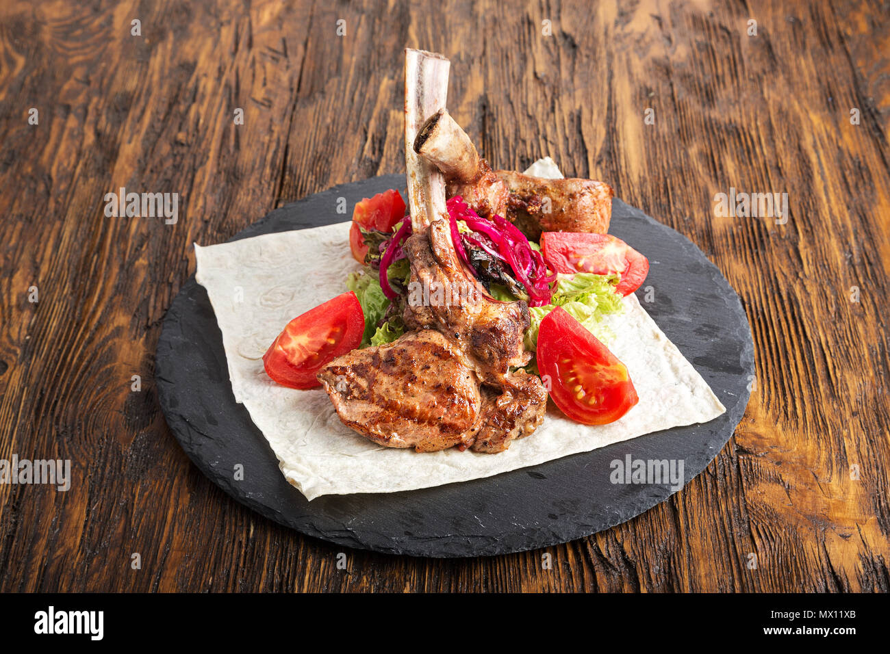 Ribeye Steak auf den Knochen, Tomahawk, serviert mit Tomaten und Eisbergsalat auf pita auf Schiefer. Stockfoto