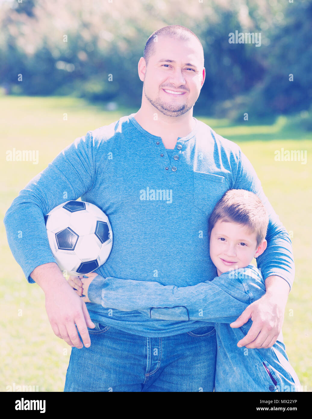 Porträt der glückliche Vater und Sohn mit Fußball auf Gras Stockfoto