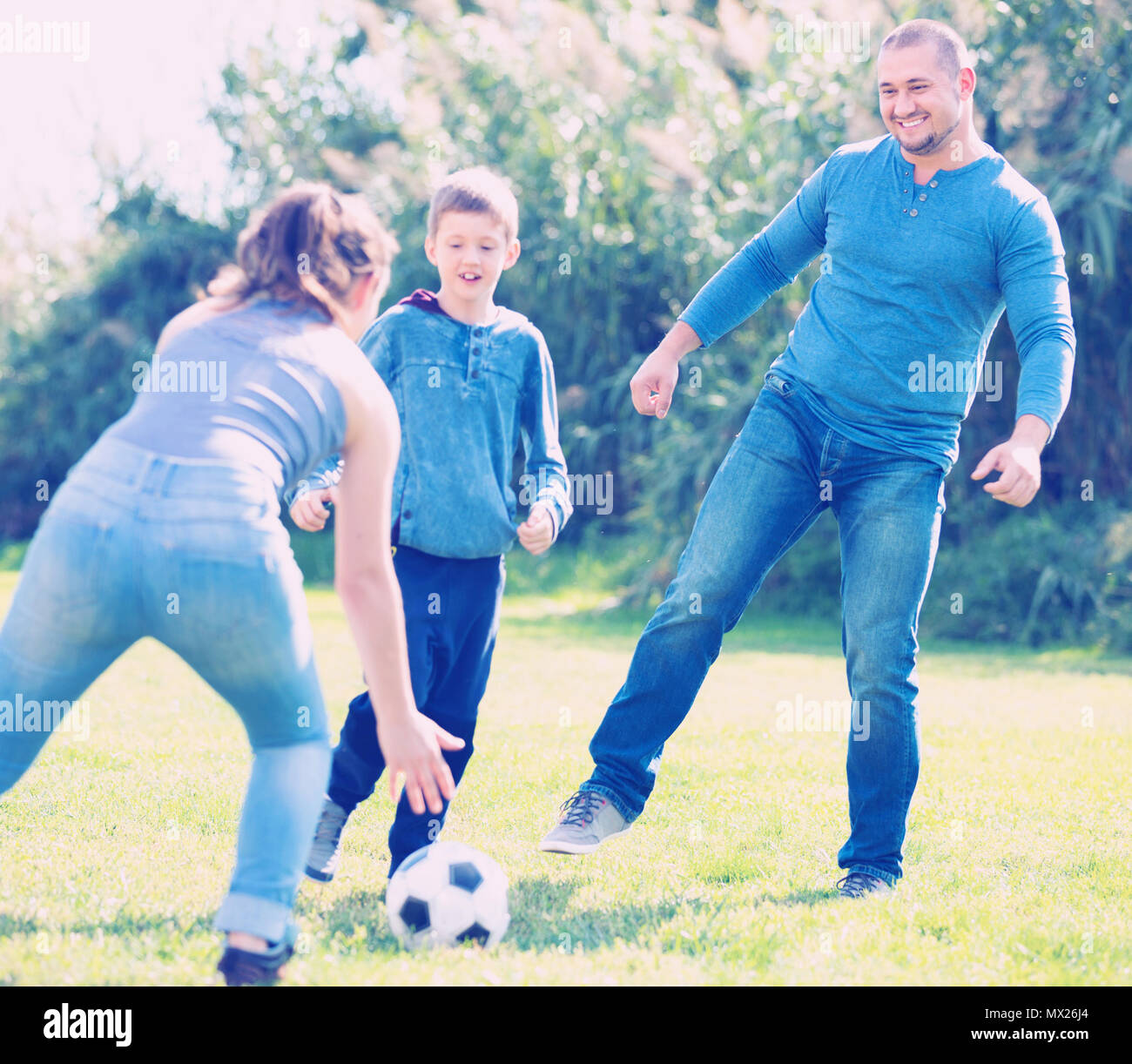 Portrait von aktiven positiven Familie Fußball spielen mit Sohn im Freien Stockfoto
