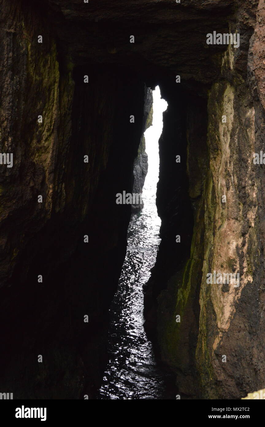 Eine Lücke in einer Höhle am Rande des Meeres lassen Licht in den dunklen Bereich. Stockfoto