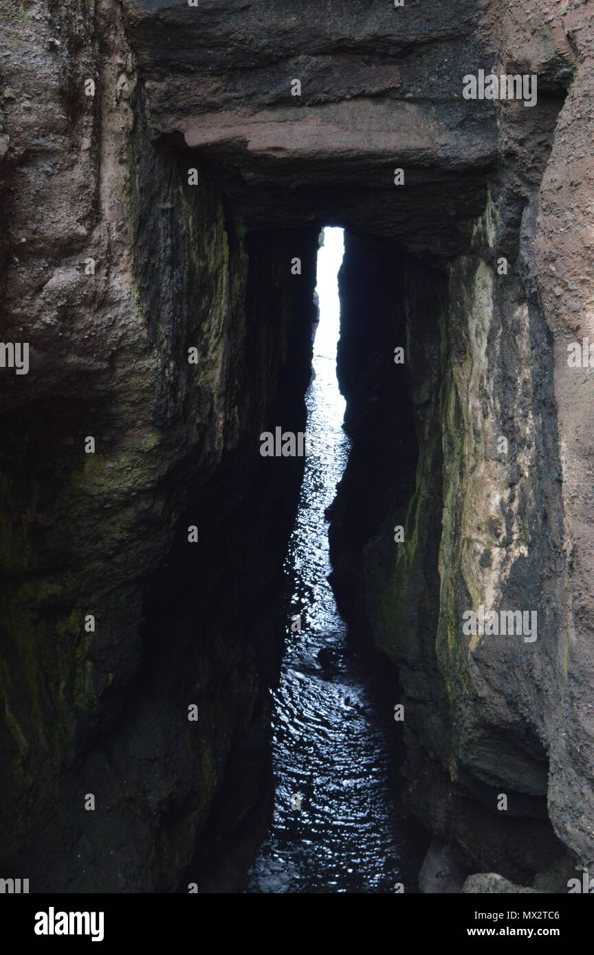 Eine Lücke in einer Höhle am Rande des Meeres lassen Licht in den dunklen Bereich. Stockfoto