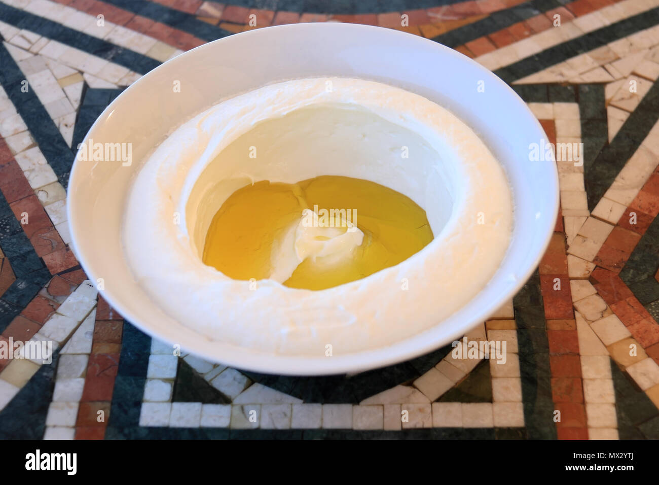 Eine frische labneh Schüssel mit Olivenöl auf einem Mosaik Tisch. Es ist eine traditionelle libanesische Frühstück. Stockfoto
