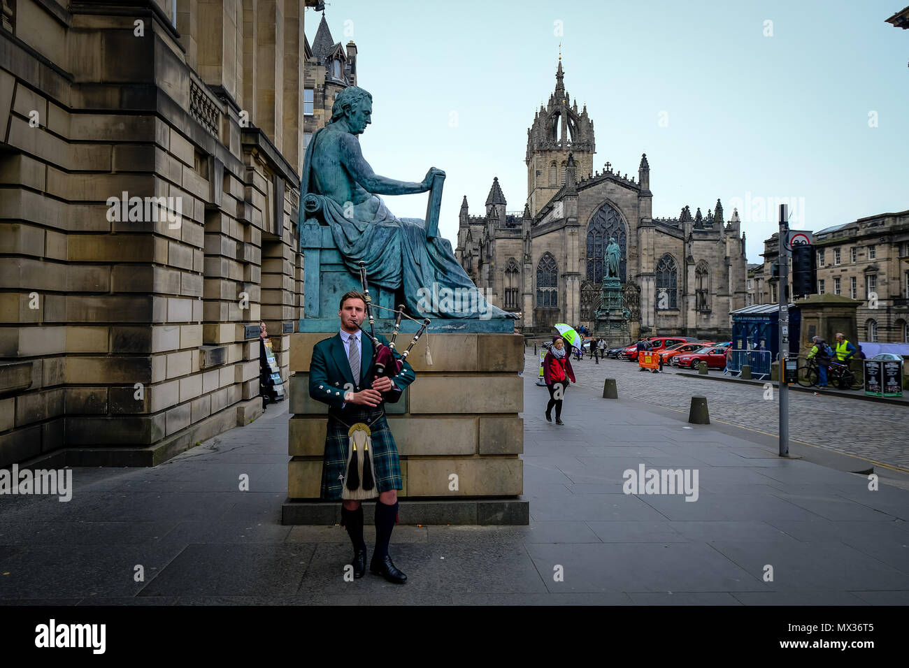 Edinburgh, Schottland - April 27, 2017: Dudelsack mit traditionellen schottischen highlander Roben spielen auf der Royal Mile, mit St. Giles Kathedrale im Hintergrund Stockfoto