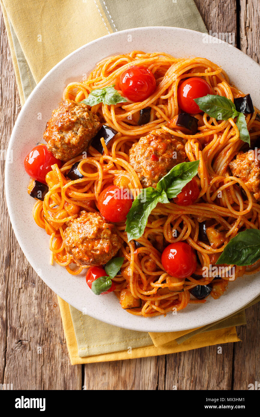 Spaghetti mit Fleischbällchen, Gemüse in Tomatensauce close-up auf einem Teller auf dem Tisch. Vertikal oben Ansicht von oben, rustikalen Stil Stockfoto