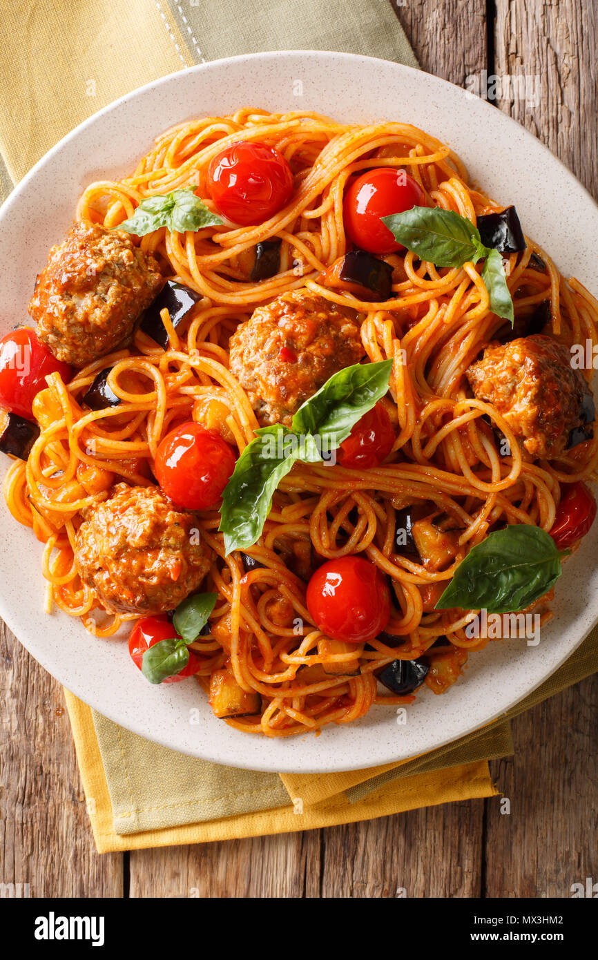 Köstliche traditionelle Pasta Spaghetti mit Fleischbällchen, Auberginen in Tomatensauce close-up auf einem Teller auf dem Tisch. Vertikal oben Ansicht von oben Stockfoto