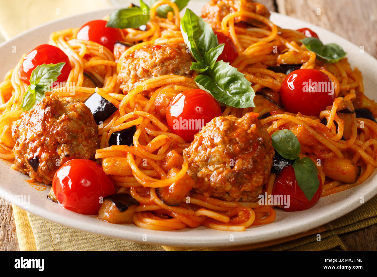 Köstliche traditionelle Pasta Spaghetti mit Fleischbällchen, Auberginen in Tomatensauce close-up auf einem Teller auf dem Tisch. Horizontale Stockfoto