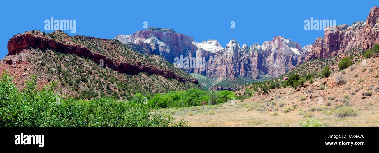 Panoramablick auf sandigen Senke und grüne Bäume, die von steilen Wänden bunte Berge unter strahlend blauen Himmel gesichert. Stockfoto