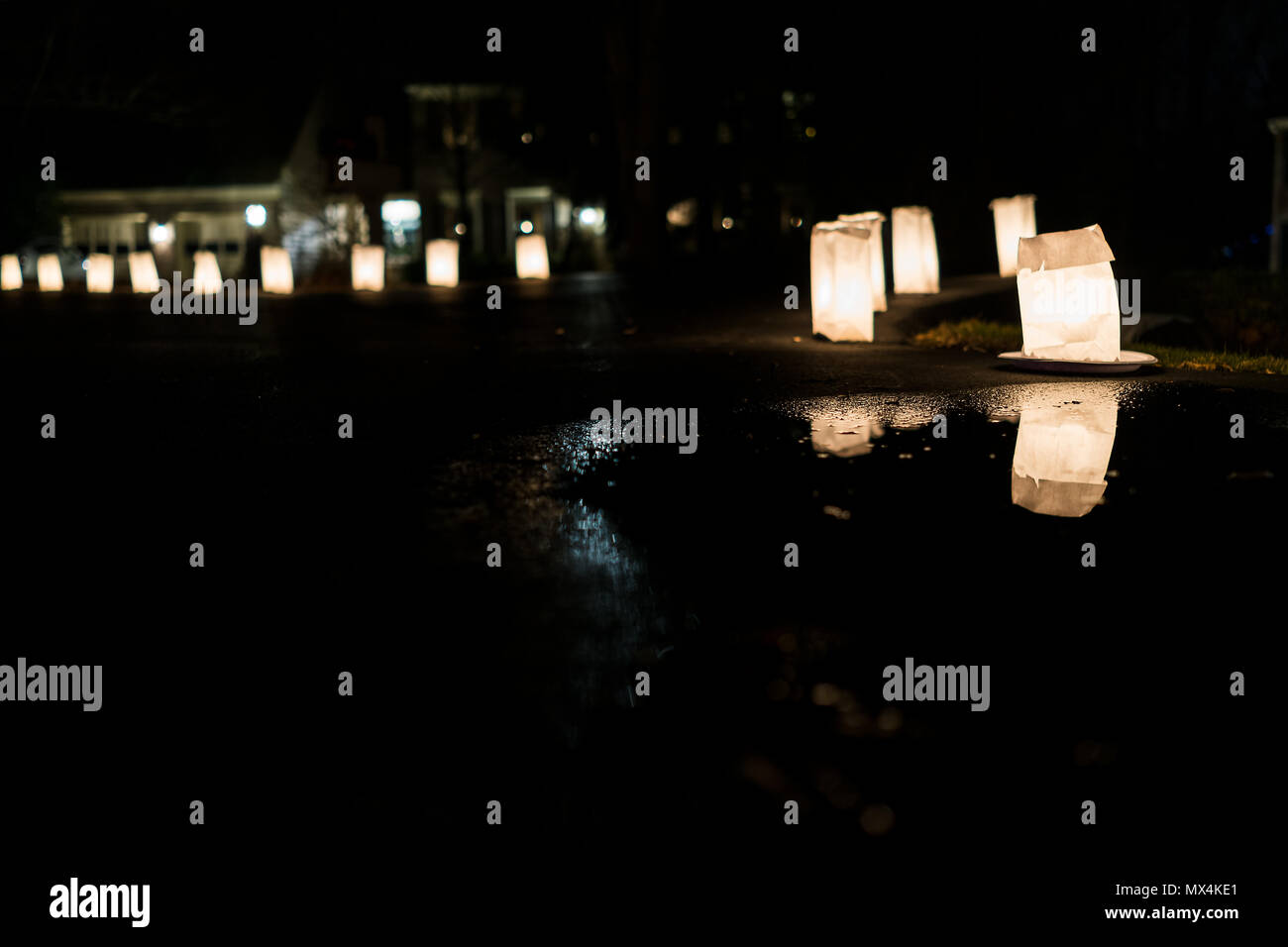 Heiligabend Kerzenlicht Flamme closeup Reflexion in der Pfütze beleuchtet in Papiertüten in der Nacht in Zeile Futter Straße Straße von Wohn- neighborhoo Stockfoto