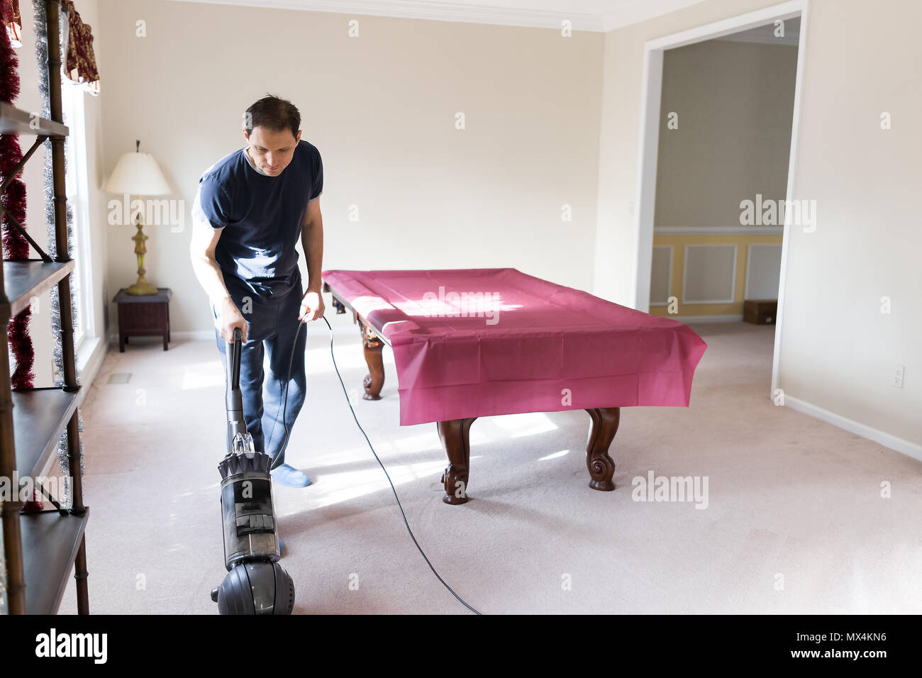 Junger Mann Haus Mann bleiben zu Hause Vati Staubsaugen mit Vakuum auf dem Teppich boden, Innen, Innere des Haus Wohnzimmer Billard, das häusliche Leben Stockfoto