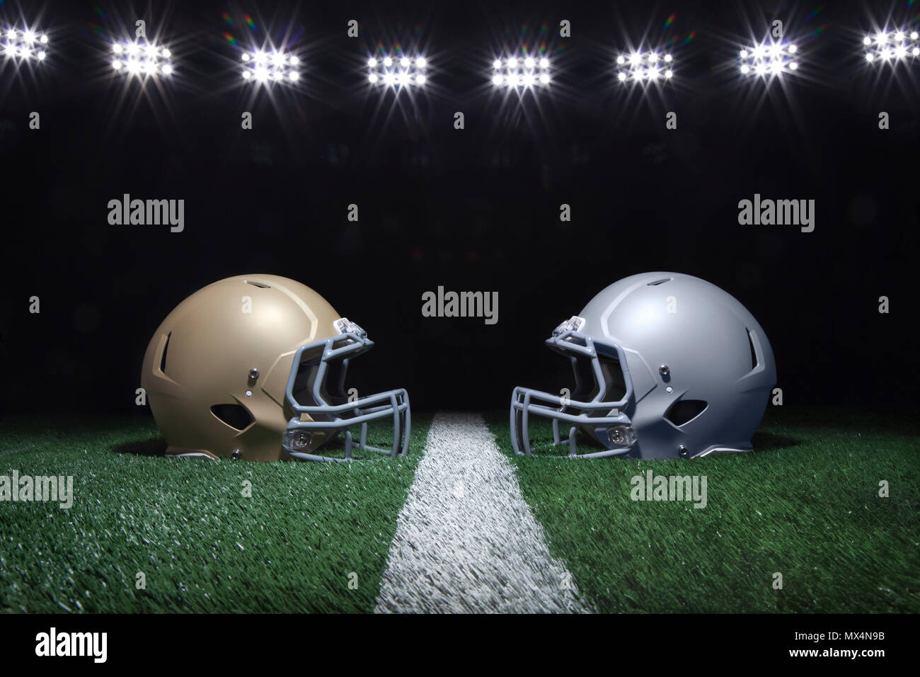 Gold und Silber Fußball Helme mit Blick auf ein Yard Linie unter Stadion Lichter in der Nacht Stockfoto
