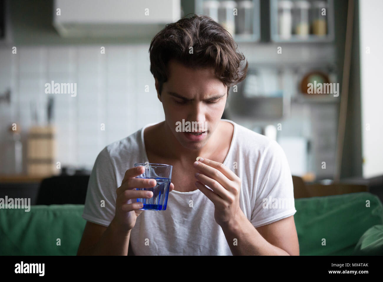 Tausendjährige Mann die Pille Schmerz zu Hause zu entlasten Stockfoto