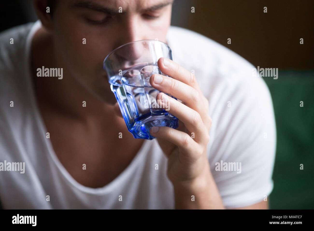 Junger Mann Durst dehydriert Holding Glas trinken ... Stockfoto