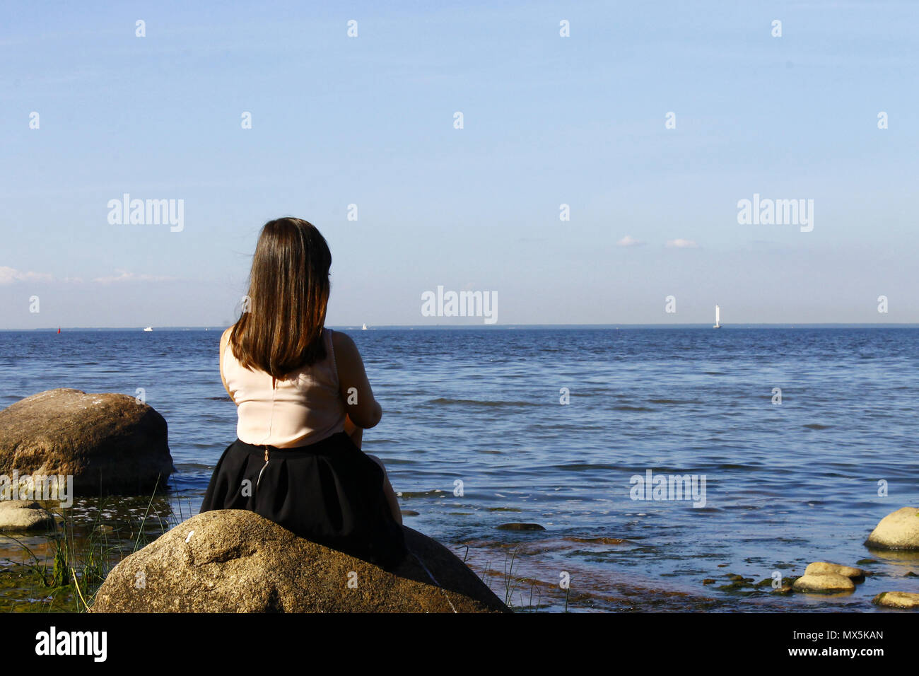 Mädchen sitzt auf einem Stein, am blauen Meer. Sommer, Sonne, s Stockfoto