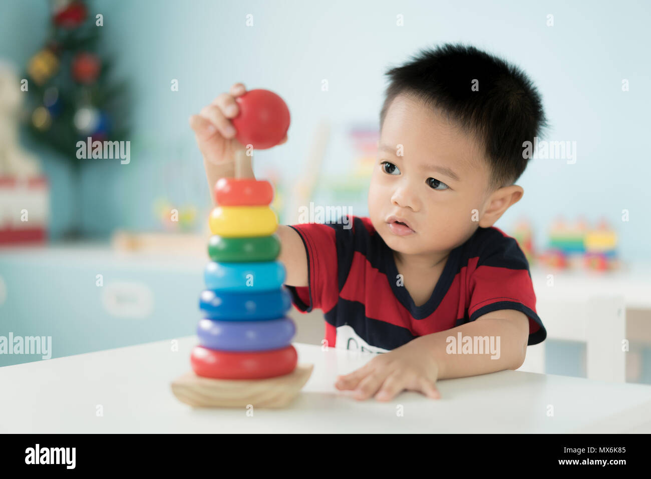 Adorable asiatischen Kleinkind Baby Junge sitzt auf einem Stuhl und Spielen mit Farbe entwicklungspolitischen Spielzeug zu Hause. Stockfoto