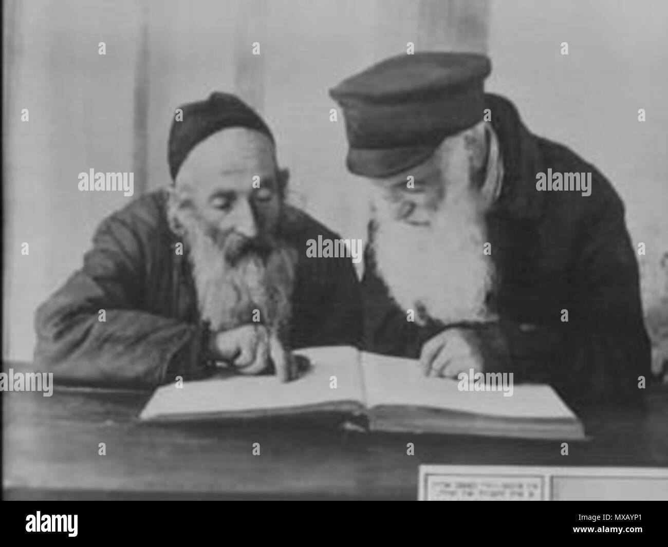 . Englisch: ('Jewish Daily Forward" Beschriftung in Jiddisch:) "... Sie erhalten in einem Kapitel der Mischna, die in der Schule." (auf Deutsch:) "Zwei ehrwürdige Juden brütete über einen hebräischen religiösen Arbeiten." (Aus einem Foto Essay mit dem Titel "Bilder von der gegenwärtigen Leben in Pinsk, Polen.') עברית: (כיתוב ביידיש, פאָרווערטס בעיתון'':) "הם קוראים בפרק במשנה בבית הכנסת." (מאסופת תמונות תחת הכותרת" תמונות של חיי היומיום כיום בפינסק, פולין"). In New York "forverts" am 19-Okt-1924 veröffentlicht. Alter Kacyzne 333 Kac 1924-10-19 Pinsk Juden lesen der Mischna Stockfoto