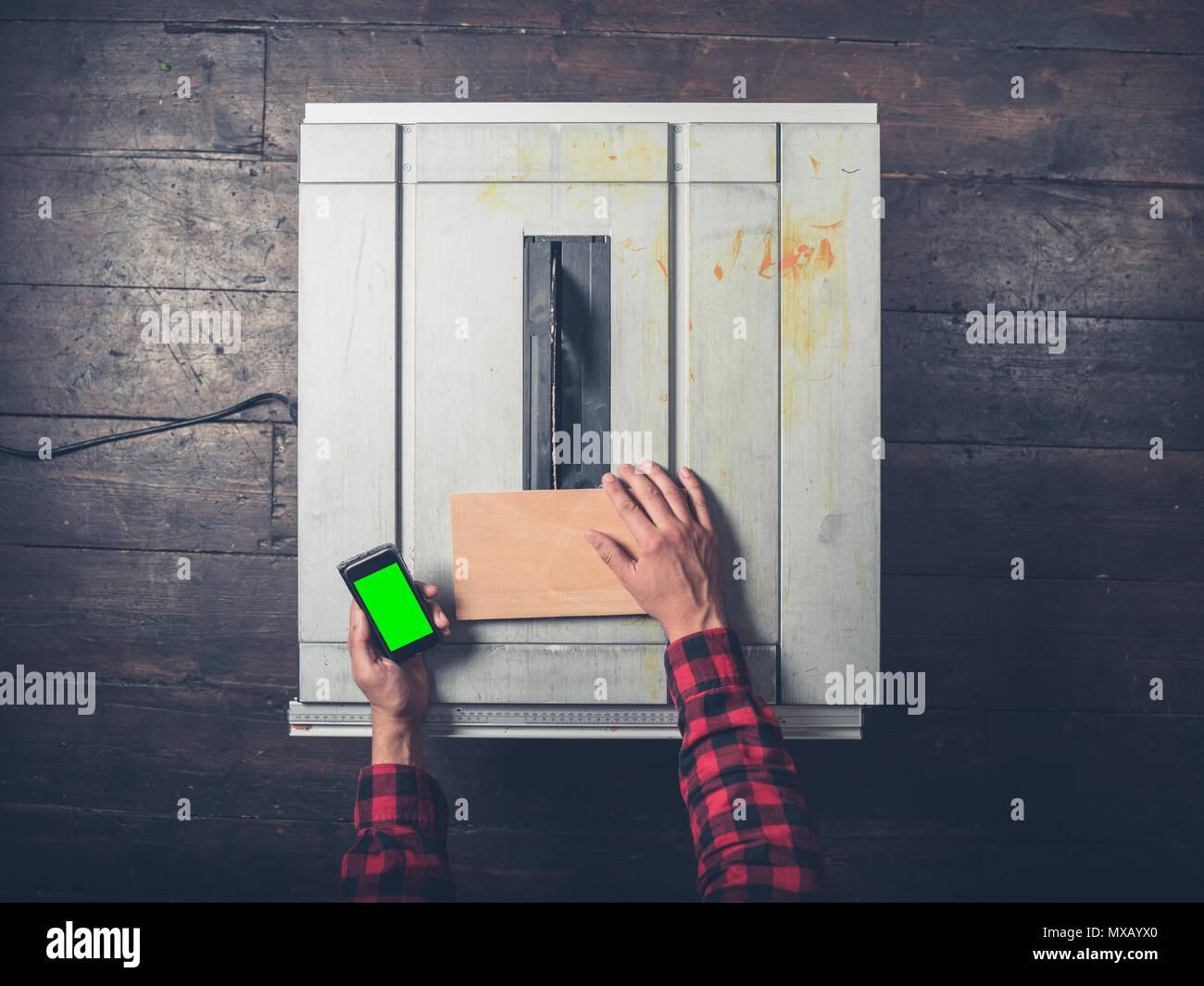 Ein junger Mann einen tablesaw hält eine Chroma Key smart phone Stockfoto