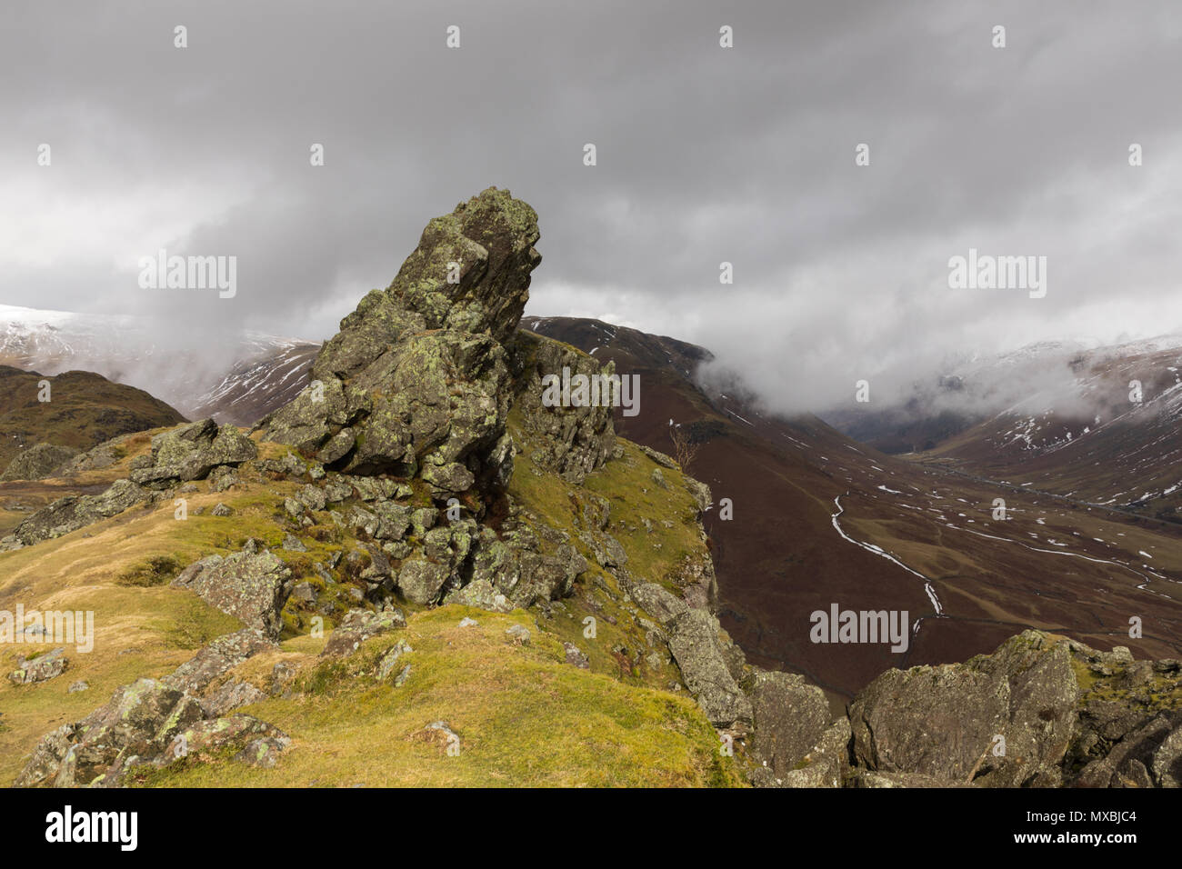 Helm Crag in Easedale im Lake District, in der Nähe von Grasmere, ist ein beliebtes Ziel für Wanderer. Der Schnee fiel in der Ferne. Stockfoto