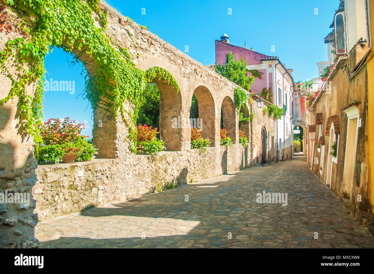 Schöne alte Steinmauer mit Bögen und Blumen auf alte europäische Straße, Ravello, Amalfi Küste, Italien Stockfoto