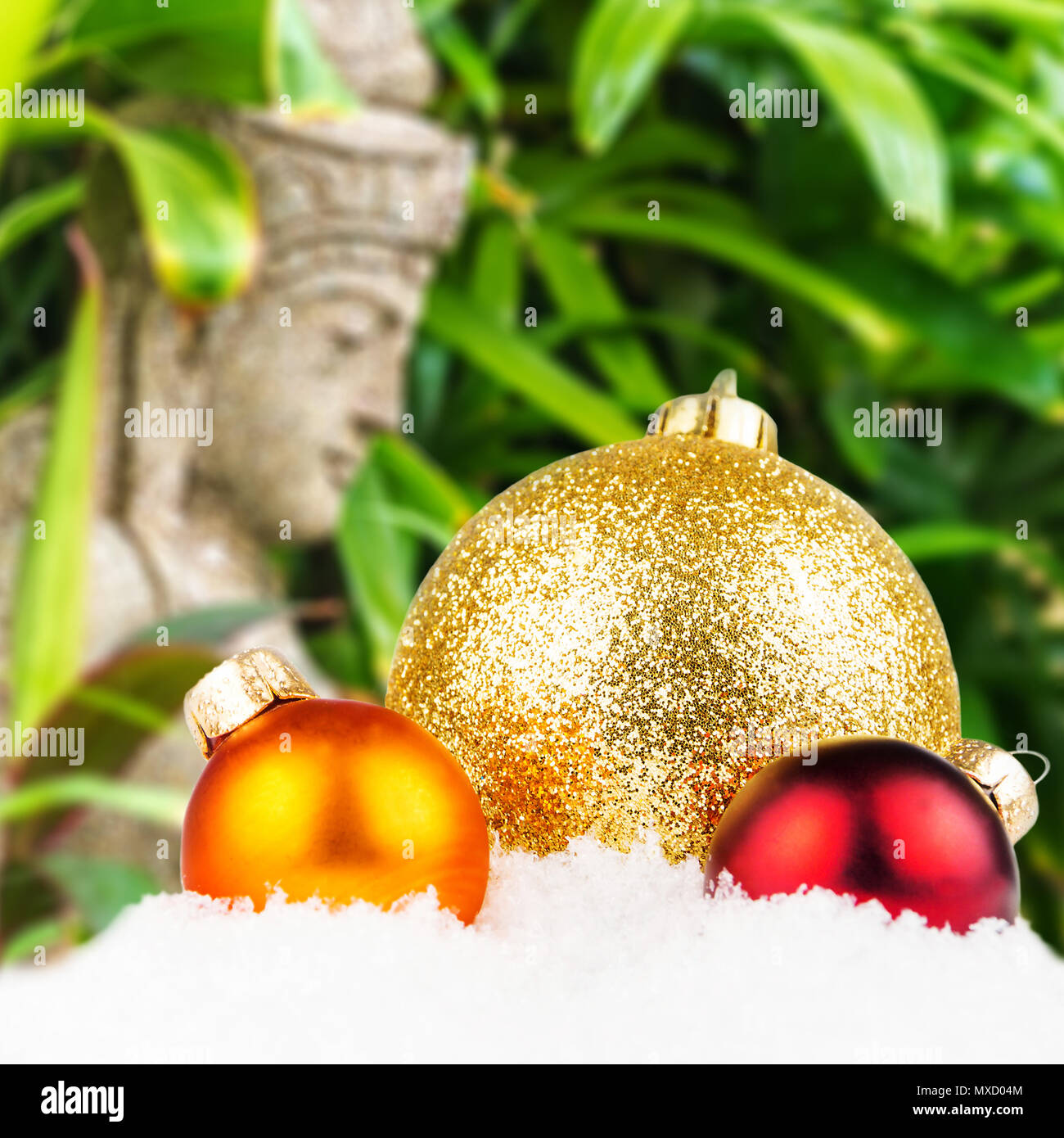 Thema Weihnachten mit balinesischer Kunst unscharfen Hintergrund, typisch balinesischen Statue in den Hintergrund und die drei bunten Weihnachtskugeln in der Front Stockfoto