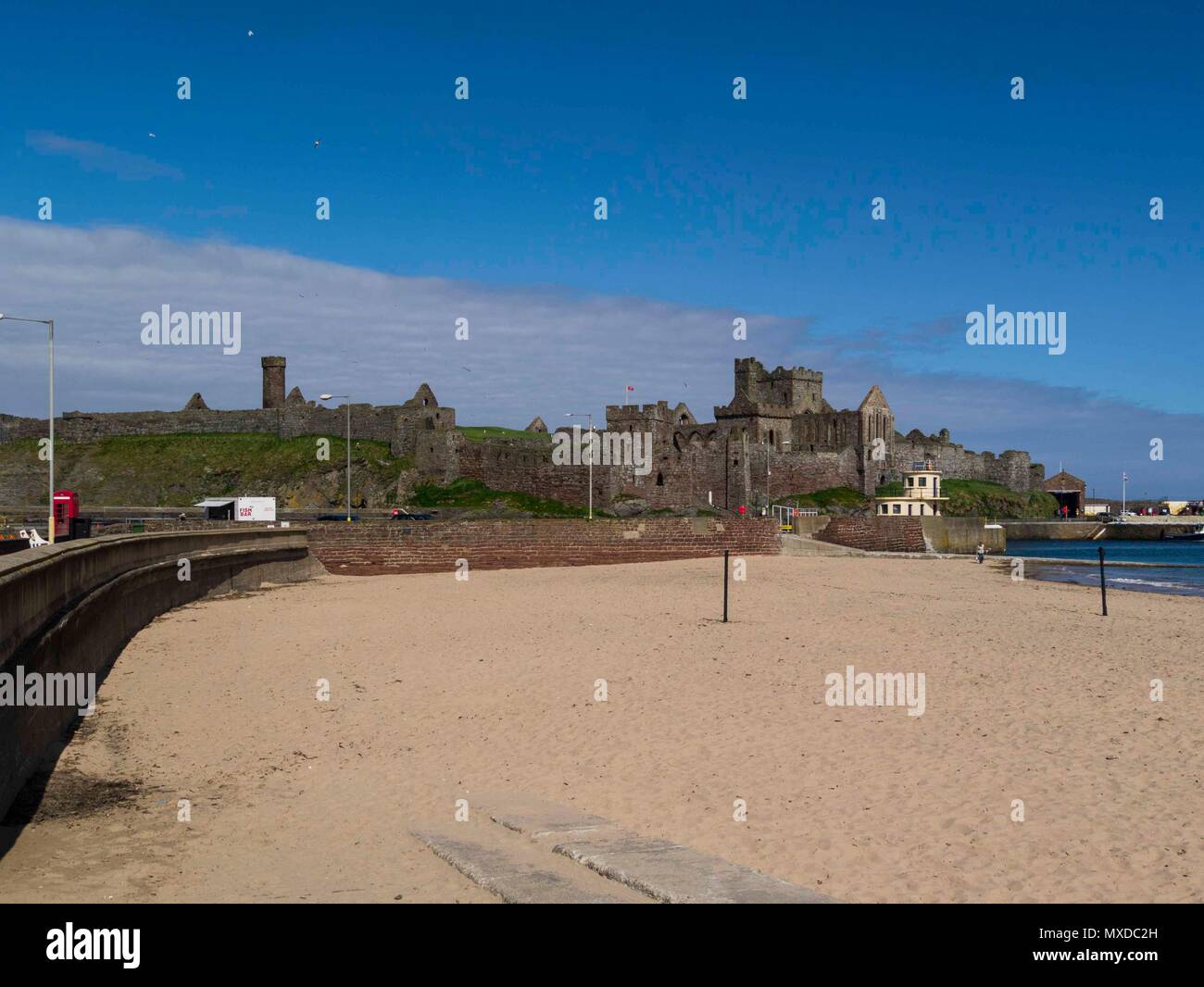 Blick entlang sauberen Sandstrand Richtung beeindruckende Peel Castle auf St. Patrick's Isle, an einem wunderschönen Tag der Insel Man Stockfoto