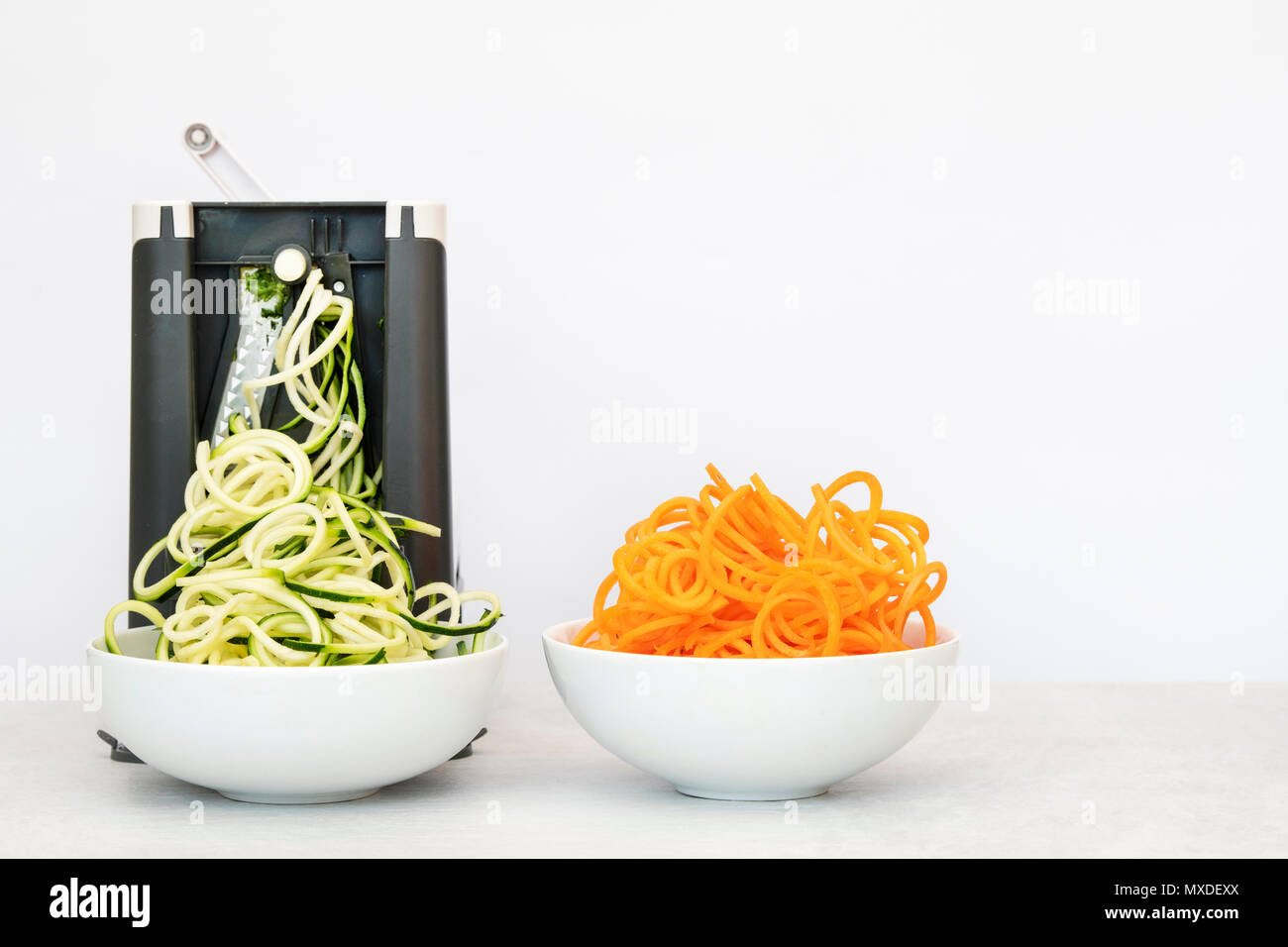 Spiralizing Zucchini und Karotten vor einem weißen Hintergrund Stockfoto